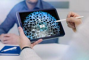 Ein Mensch hält einen Tablet-Computer mit der Abbildung eines virtuellen Startknopfes für den Digitalen Zwilling in der einen Hand und macht sich bereit, diesen zu betätigen. 